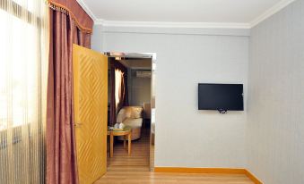 The room includes sliding doors, a TV, and a table in the living area adjacent to the bedroom at Yile Hotel