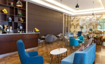 a modern lounge area with blue chairs , a marble coffee table , and a bar in the background at Kusatsu Hotel