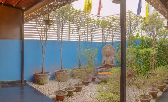a garden with a blue wall , white pebbles , and various potted plants under a lattice at The Presidency