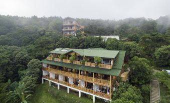 an aerial view of a large wooden house nestled in a lush green forest , surrounded by trees at Hotel Belmar