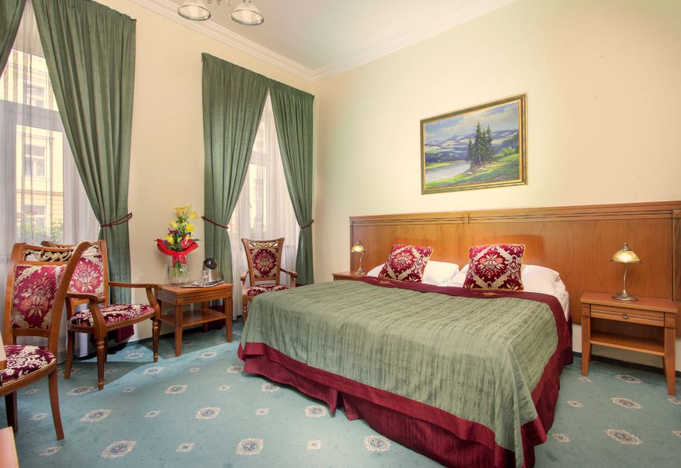 a large bed with a wooden headboard and green linens is in the middle of a room with chairs , curtains , and a painting on at Green Garden Hotel