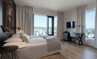 a large bed with a white comforter is in the middle of a room with wooden floors and a window at Scandic Havet