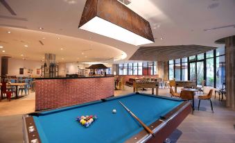 a pool table is set up in a room with brick walls and a high ceiling at Hotel Cham Cham