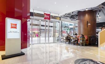 The view from inside shows the entrance to a restaurant with tables and chairs in front at ibis Hong Kong Central and Sheung Wan Hotel