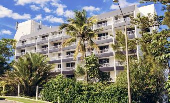 a large , white apartment building with balconies and palm trees in front of a street at Greenmount Beach House