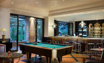 a pool table is in the center of a room with bar stools and large windows at Melia Purosani Yogyakarta