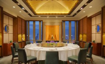The room has large windows and round tables set for four in the dining area, providing a view at Grand Hyatt Shanghai