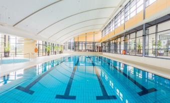 an empty indoor swimming pool surrounded by glass walls , with sunlight streaming in through the windows at Aitken Hill