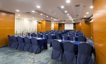A spacious ballroom is arranged with blue chairs and tables for an event at Shanghai Shaanxi Business Hotel