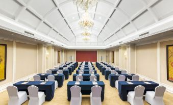 A spacious event room is arranged with a head table adorned with blue and white chairs at Grand Metropark Guofeng Hotel, Tangshan