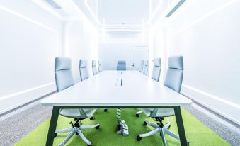 The meeting room is currently vacant and features white walls, a conference table surrounded by green chairs at OASIS AVENUE – A GDH HOTEL