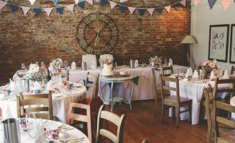 a dining room with tables and chairs set up for a wedding reception , featuring a clock on the wall at Blue Pigeons