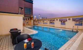 There is a swimming pool with tables and chairs located by the edge, offering a view of the outdoors during the night at Ramada Hong Kong Grand View