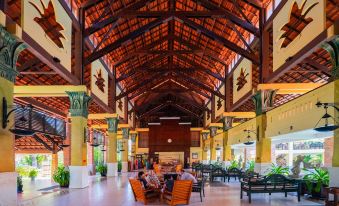 a large , well - lit room with high ceilings and wooden beams , filled with people sitting around tables at Pandanus Resort