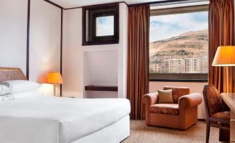 a hotel room with a king - sized bed and a view of a mountain through the window at Sheraton Hotel
