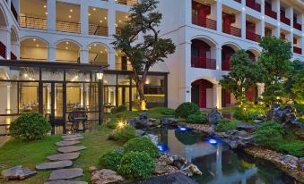 a courtyard with a small pond surrounded by trees and plants , creating a serene atmosphere at Senna Hue Hotel