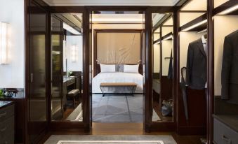 a bedroom with a bed , nightstand , and mirror is visible through an open doorway at Hotel the Peninsula Paris