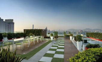 The upper floor terrace on the rooftop offers tables and chairs with a view of the city at The Park Lane Hong Kong a Pullman Hotel