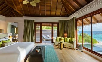 a spacious bedroom with a bed , a couch , and a tv . the room is well - appointed and inviting at Dusit Thani Maldives
