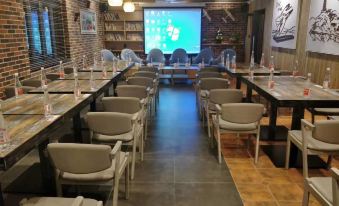 The restaurant features tables and chairs arranged in front of a large screen, allowing customers to dine while enjoying movies or other entertainment at Maker Hotel