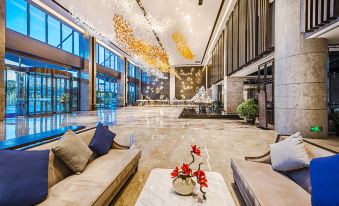 The lobby features a sleek, modern design highlighted by a prominent chandelier and glass panels at Hainan Guest House No.2 Building