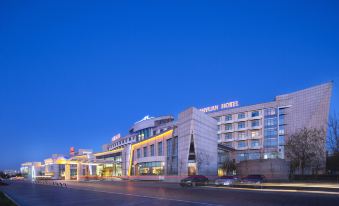 The hotel is surrounded by other buildings, and at night, the exterior view shows the hotel in front at Tianyuan Hotel