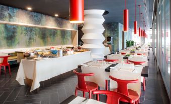 a modern restaurant with red chairs and tables , white tablecloths , and hanging light fixtures at Glam Milano