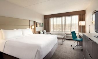 a large , white bed is in a room with a blue chair and a desk at Crowne Plaza Englewood, an IHG Hotel