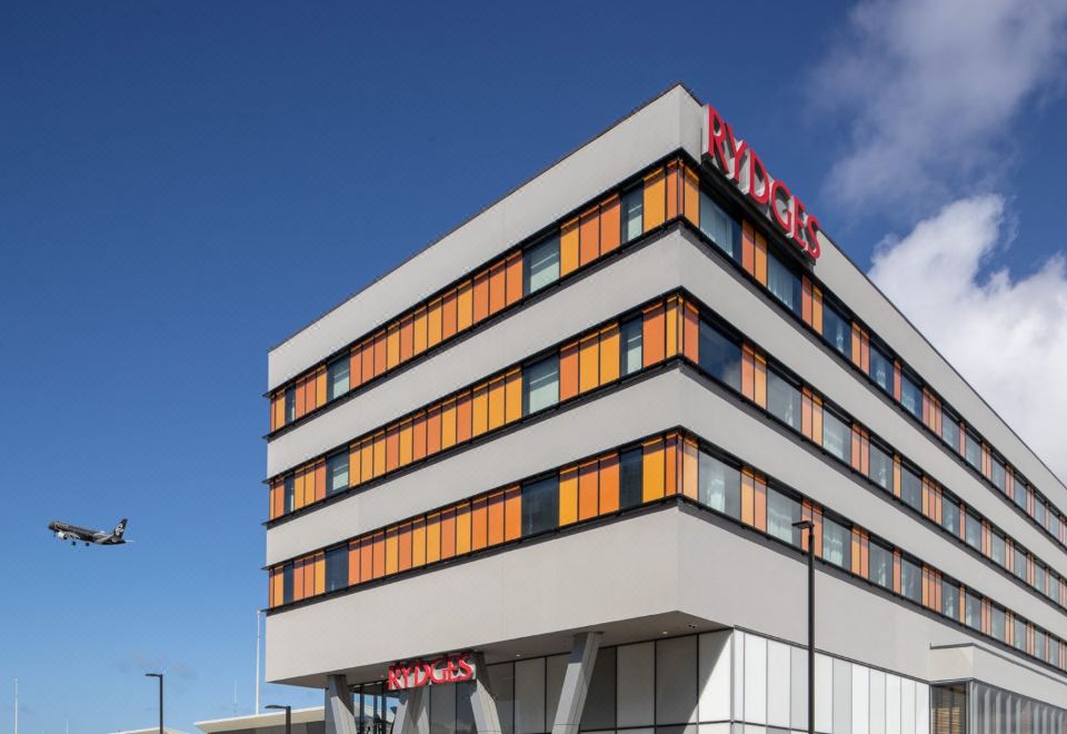 "a modern , white building with orange windows and a red sign that reads "" ryka "" on top" at Rydges Wellington Airport, an EVT hotel