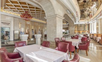 a large dining room with multiple tables and chairs , some of which are covered in white tablecloths at Regency Hotel