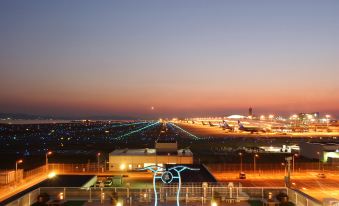 a panoramic view of an airport at sunset , with airplanes taking off from the runway and leaving their lights on at Hotel Nikko Kansai Airport