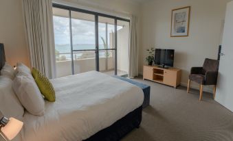 a bedroom with a large bed , a television , and a window overlooking the ocean at Aurora Ozone Hotel Kangaroo Island