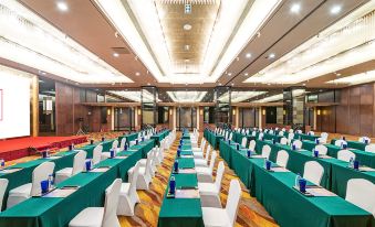 a large banquet hall with green tables and white chairs , set up for a formal event at Millennium Harbourview Hotel Xiamen