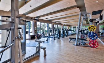 a well - equipped gym with various exercise equipment , such as treadmills , weight machines , and benches , as well as a dining area at Dusit Thani Pattaya