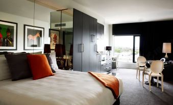 a hotel room with a king - sized bed , a closet , and a door leading to a balcony at The Cullen Melbourne - Art Series