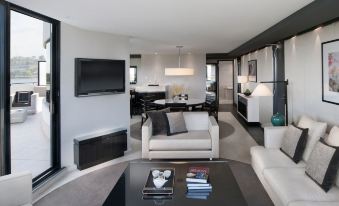 a modern living room with a large flat - screen tv mounted on the wall , a couch , and a dining table at Crown Metropol Perth