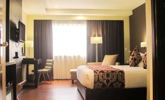 a modern hotel room with a large bed , wooden floors , and black curtains , along with a desk and chair at Brentwood Suites
