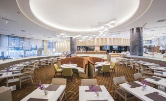 a large , modern restaurant with multiple dining tables and chairs , as well as a bar area at Novotel Taipei Taoyuan International Airport