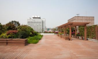 A large park with wooden walkways and benches is located next to an empty space at Merchant Marco Edgelake Hotel