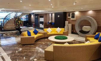 a large , modern lounge area with yellow and blue couches and chairs , surrounded by marble flooring at Executive Hotel