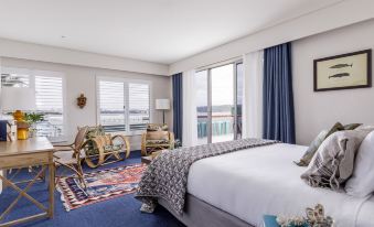 a hotel room with a king - sized bed , a chair , and a view of the ocean at Watsons Bay Boutique Hotel