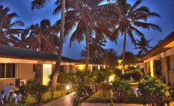 a tropical resort at night , with palm trees and buildings lit up by lights on either side at Sunset Beach Hotel