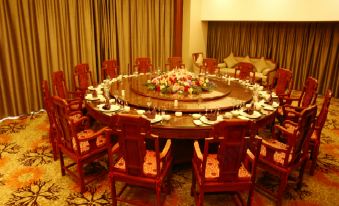 a large round table with a centerpiece of flowers and plates is surrounded by red chairs in a room at Sunshine Hotel
