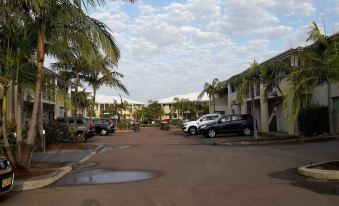 a residential area with cars parked on the street , surrounded by palm trees and other buildings at Oaks Port Stephens Pacific Blue Resort