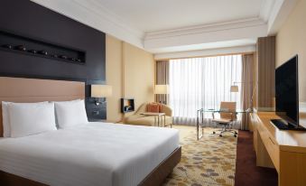 A spacious room is furnished with a bed, desk, and chair in the center, resembling an oriental style at Courtyard by Marriott Shanghai Central