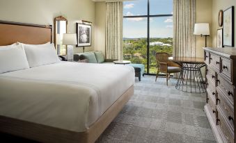 a large bed with white linens is in a hotel room with a window and chairs at Omni Barton Creek Resort and Spa Austin