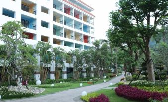 a modern , white building with red and green accents , surrounded by lush greenery and modern landscaping at Hotel Cham Cham