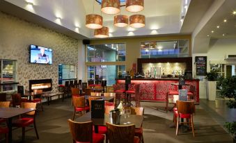 a large , well - lit restaurant with multiple dining tables and chairs , as well as a bar area at Garden Hotel