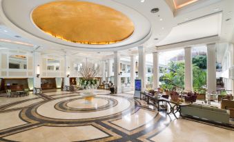 a grand hotel lobby with marble floors , gold ceiling , and a large circular light fixture at Dusit Thani Pattaya