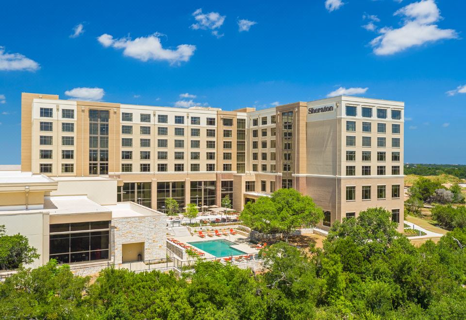 a large hotel with a swimming pool surrounded by trees , located in a city setting at Sheraton Austin Georgetown Hotel & Conference Center